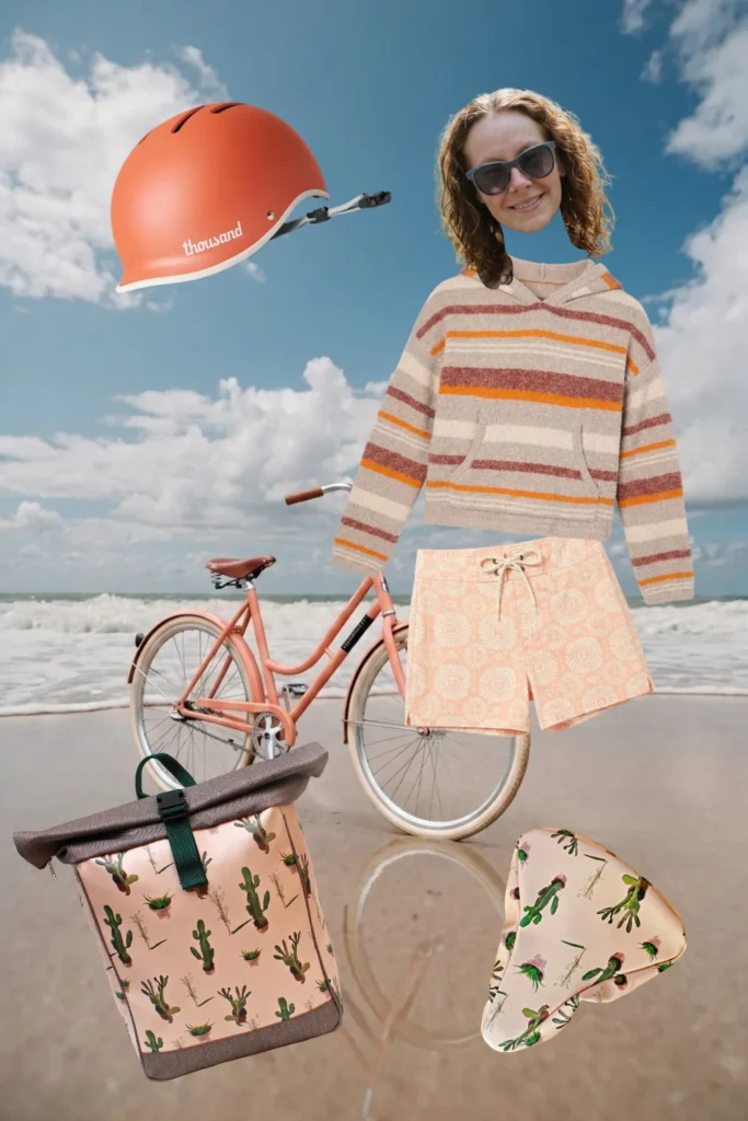 Fahrrad-Outfit am Meer: gestreifter Kapuzenpullover, apricotfarbene Shorts, oranger Fahrradhelm und Ikuri Fahrradtasche Rucksack Cactus mit Kaktus-Print und Sattelschoner