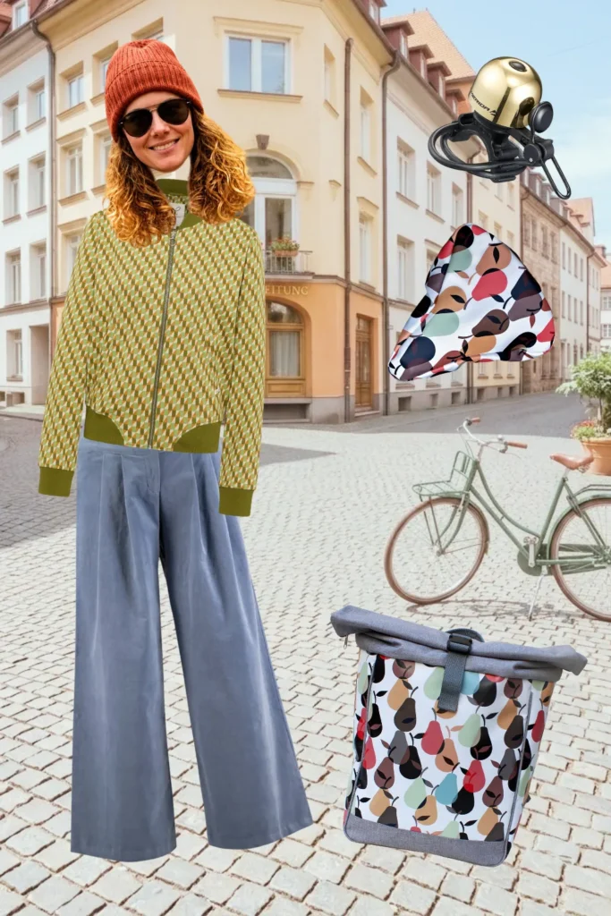 Herbst-Outfit fürs Fahrrad: gemusterte Blousonjacke, blaue Bundfaltenhose, goldene Fahrradklingel und bunte Ikuri Fahrradtasche Rucksack Peras mit Sattelschoner